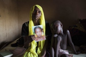 File photo shows Rachel Daniel holding up a picture of her abducted daughter Rose Daniel as her son Bukar sits beside her at her home in Maiduguri