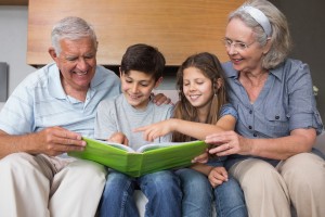 Happy grandparents and grandkids looking at album photo in the living room