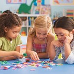 Girls (4-7) playing jigsaw puzzle in classroom