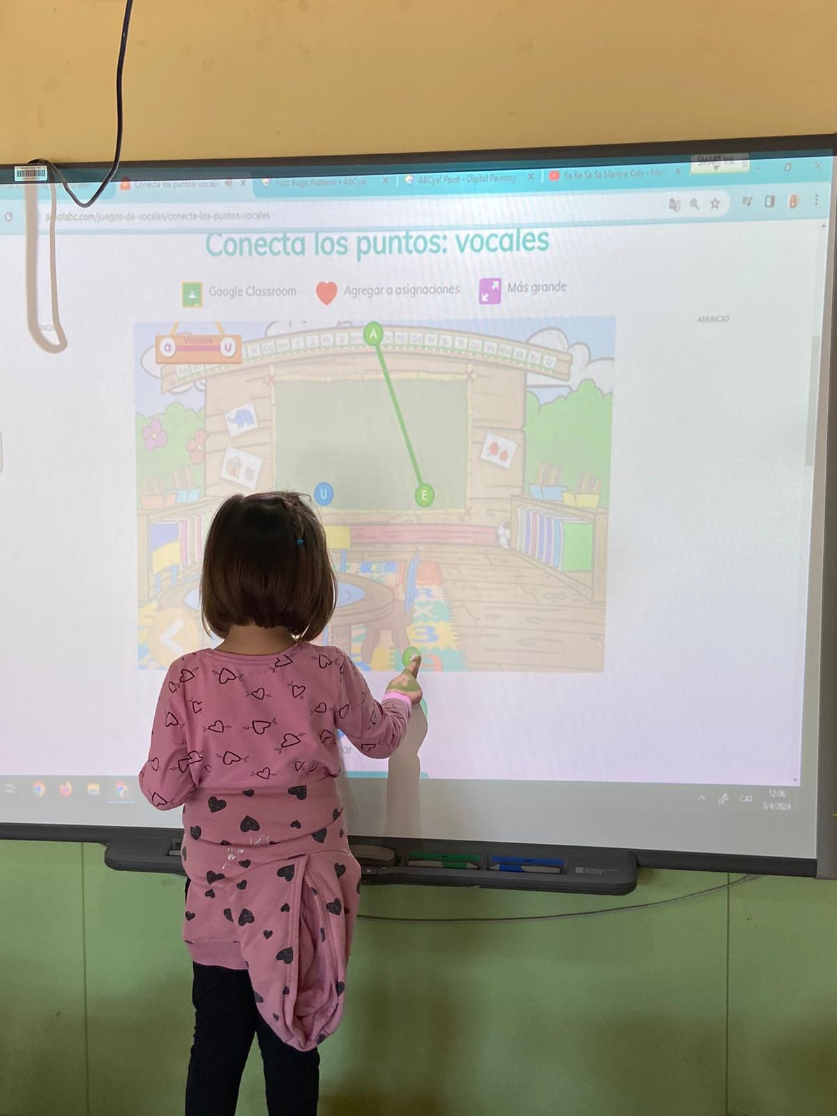 Nena realitzant una activitat a la PDI de connectar punts.